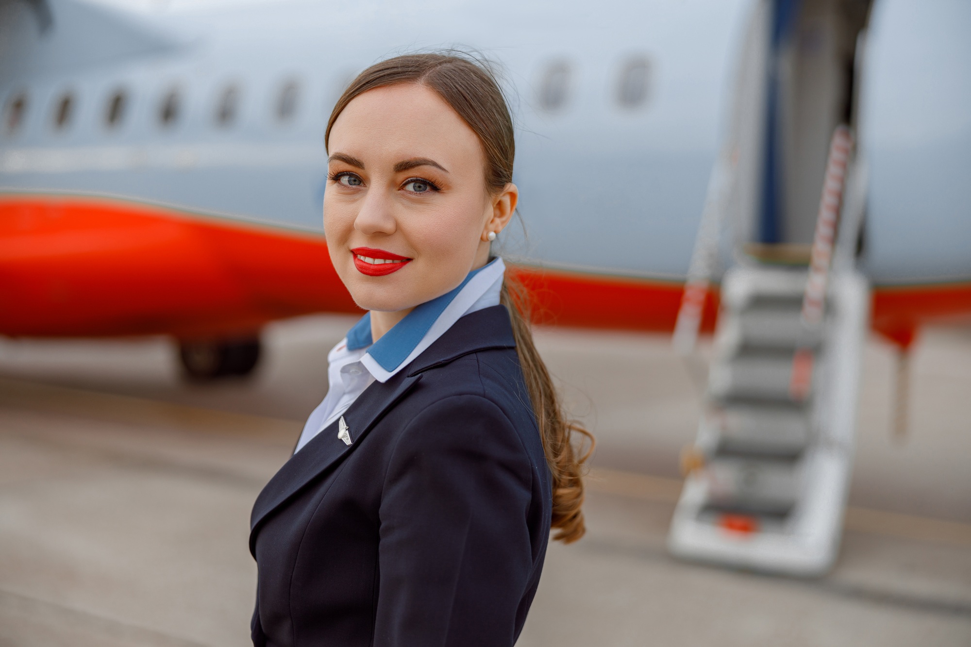 Joyful woman flight attendant standing outdoors at airport Joyful woman flight attendant standing outdoors at airport