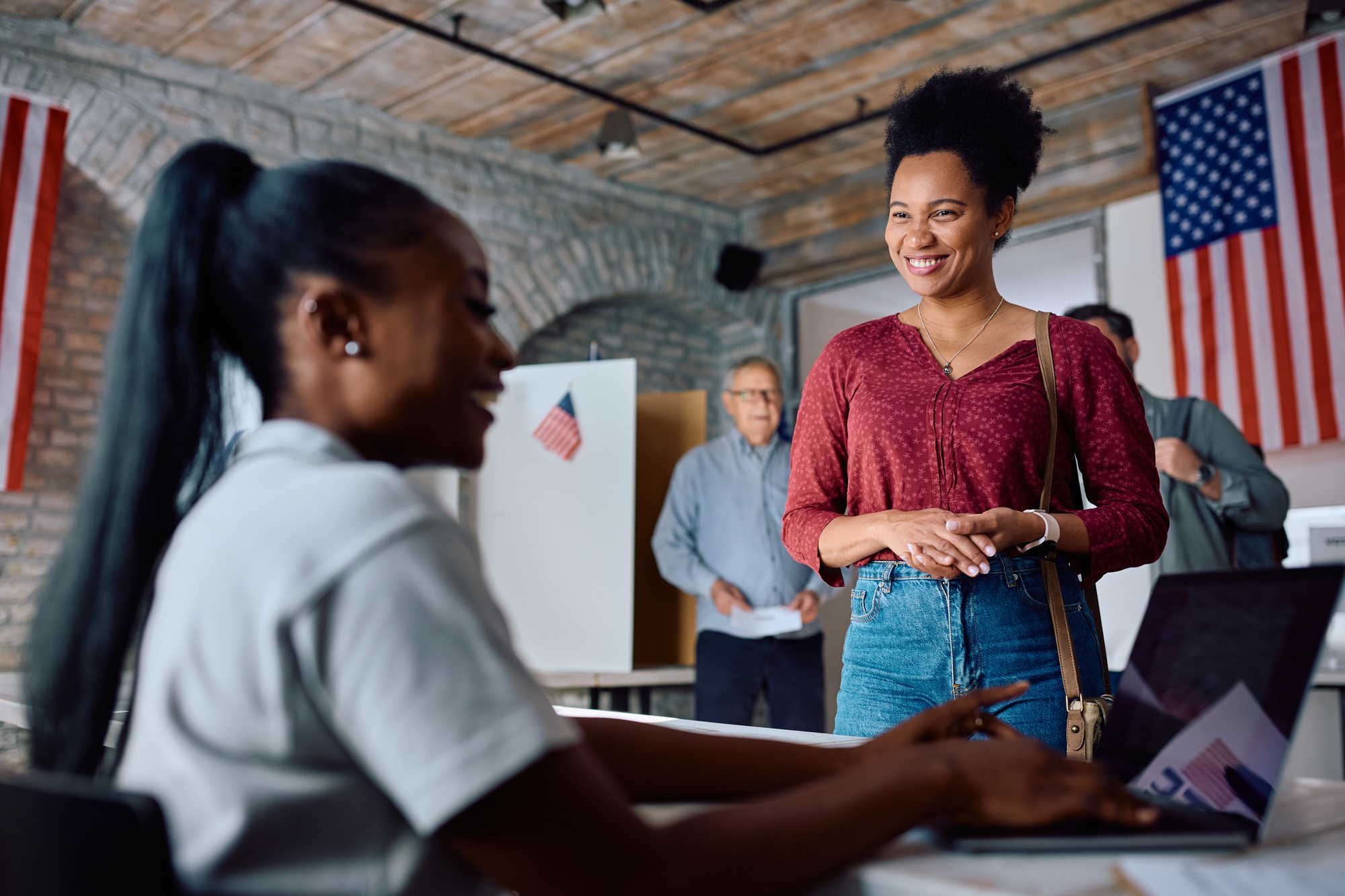 Happy black female voter coming to polling station during US elections.