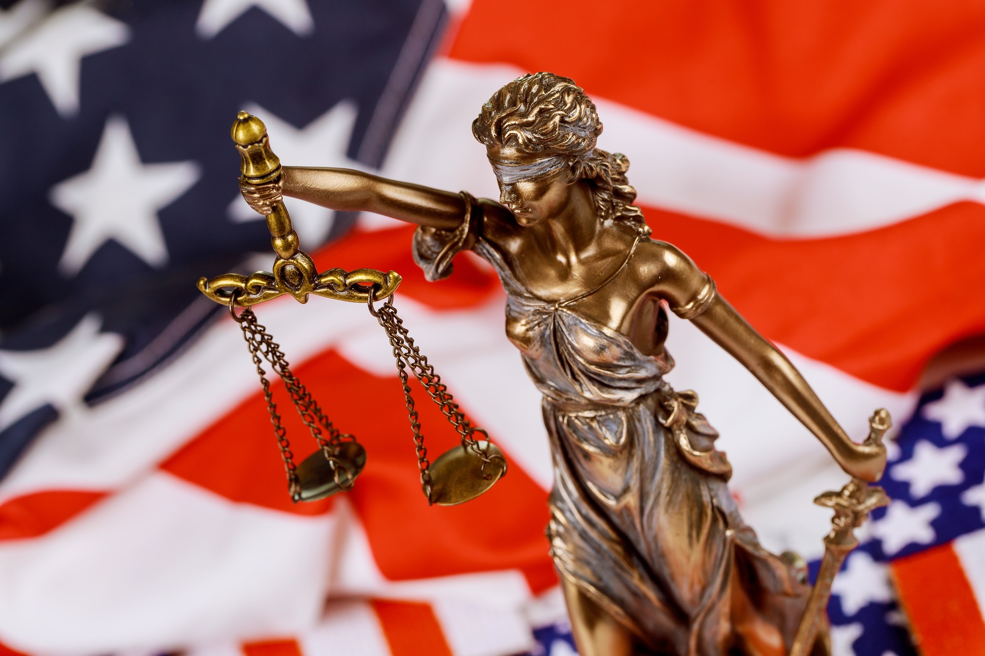 Lawyers desk statue of justice on law court in United States of America flag in background Lawyers desk statue of justice on law court in United States of America flag in background
