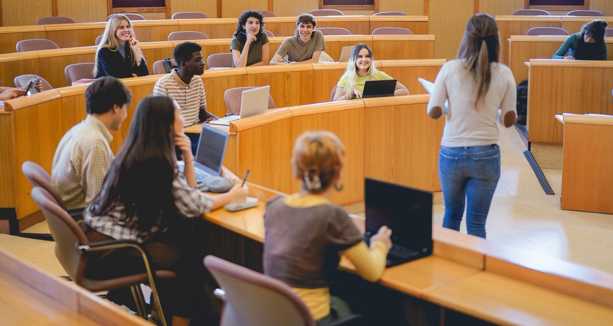 Young students working with laptop computers inside classroom at school university